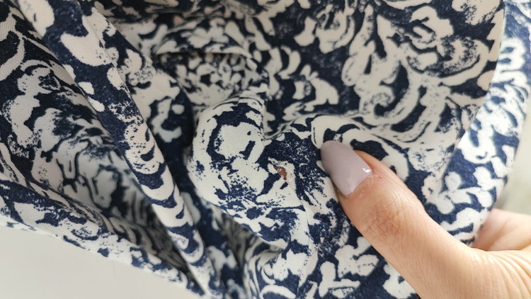 شومیز زنانه طرحدار سرمهای و سفید وارداتی کد ۱ سایز ۴۴ و ۴۶ * نمای تنخور: مدل شومیز یقه هفت دکمهدار استوک اروپایی با شلوار جین * تصویر جزئیات: نمای نزدیک از ایراد زدگی جزئی کنار دوخت بغل شومیز کد