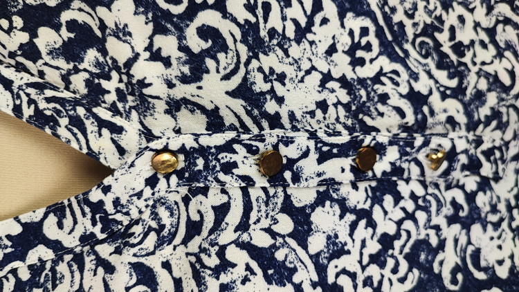 شومیز زنانه طرحدار سرمهای و سفید وارداتی کد ۱ سایز ۴۴ و ۴۶ * نمای تنخور: مدل شومیز یقه هفت دکمهدار استوک اروپایی با شلوار جین * تصویر جزئیات: نمای نزدیک از ایراد زدگی جزئی کنار دوخت بغل شومیز کد