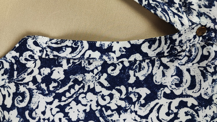 شومیز زنانه طرحدار سرمهای و سفید وارداتی کد ۱ سایز ۴۴ و ۴۶ * نمای تنخور: مدل شومیز یقه هفت دکمهدار استوک اروپایی با شلوار جین * تصویر جزئیات: نمای نزدیک از ایراد زدگی جزئی کنار دوخت بغل شومیز کد