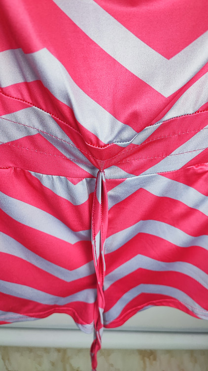 سرهمی کوتاه دکلته زنانه با طرح زیگزاگ صورتی و طوسی کد ۱۰۳۳ مناسب استایل ساحلی و راحتی * تصویر جزئیات: نمای نزدیک از کمر کشی و بند تنظیمی رامپر دکلته زنانه کد ۱۰۳۳ جهت بررسی کیفیت دوخت